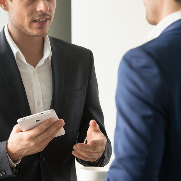 Businessman with digital tablet in hand explaining partner his position on issue, offering partnership in perspective project, sharing ideas during work negotiation. Personal exchanges with colleagues